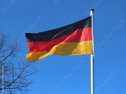 Germany flag bold and proud floating in the wind, against sunny blue sky