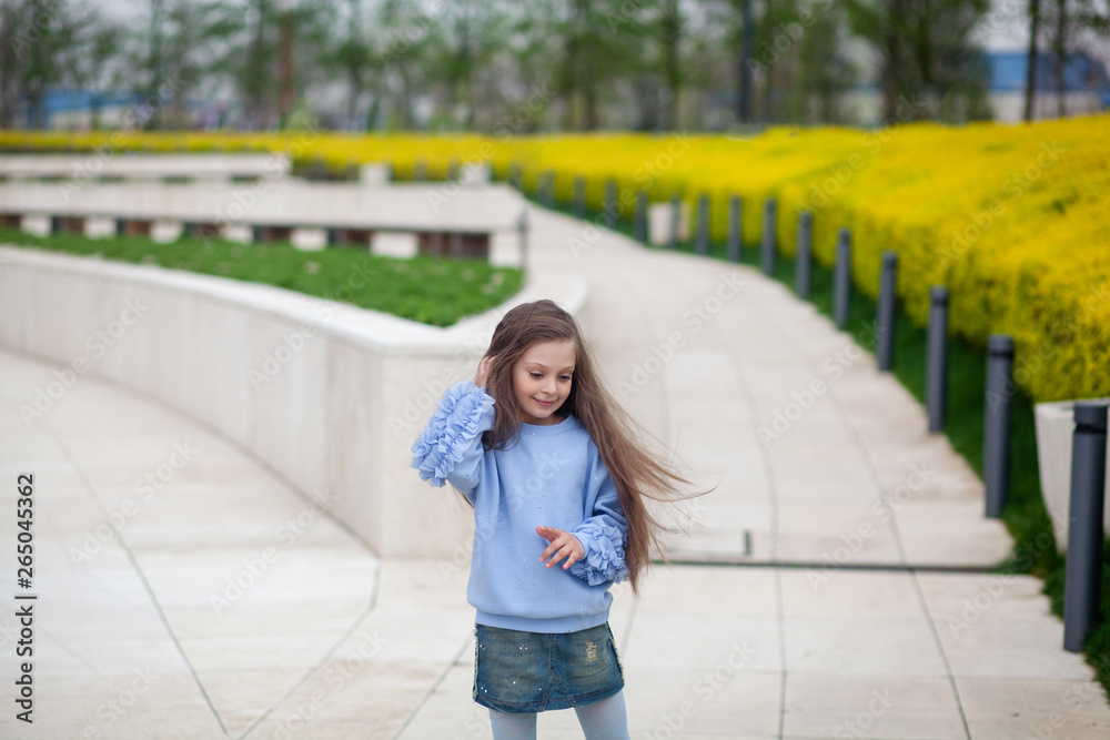 Fototapeta premium Portrait of a happy pretty girl with long beautiful hair in the park in spring