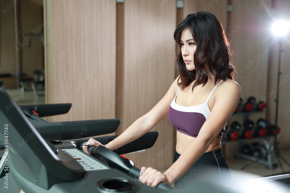 portrait of young healthy and sporty woman taking a rest after exercise in gym (this image for fitness and workout concept)