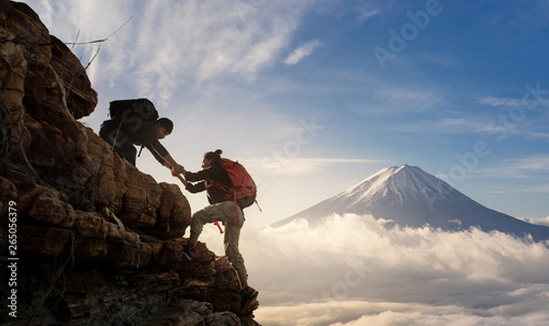 Group of Asia hiking help each other silhouette in mountains with sunlight..