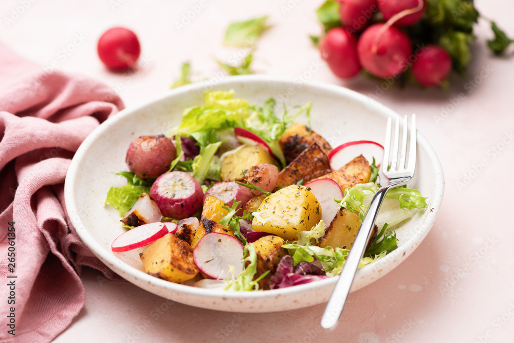 Healthy potato salad with radishes and green leaf lettuce on pink background Healthy potato salad with radishes and green leaf lettuce on pink background