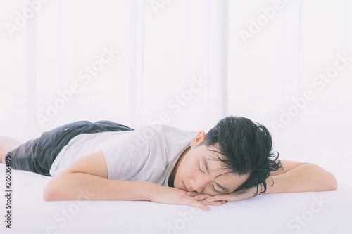 Obraz na plátně Man lie prone on bed, he in pajamas in bedroom..