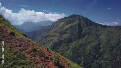 Woman walks on the mountain trail lying on the edge of the cliff with stunning valley views. The place named Little Adam's Peak in Ella, Sri Lanka photo