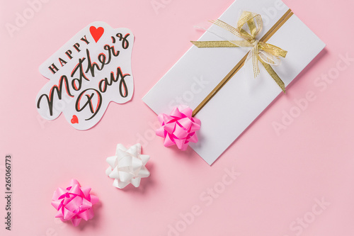 happy mother's day text, greeting card on pink background, flat lay with space for text. modern image. top view. stylish creative wallpaper.Elegant greeting card with Pink ribbon bow. Creative art.