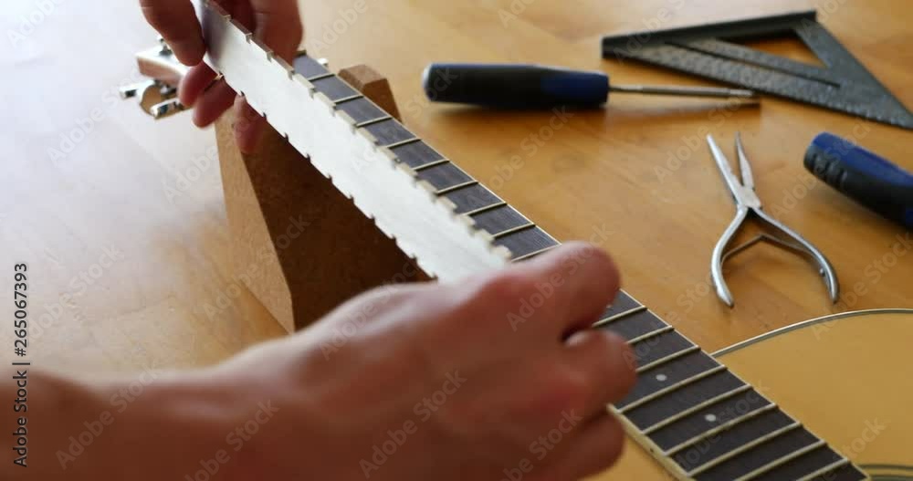 Video Stock Hands of a luthier craftsman measuring and leveling an acoustic guitar neck and