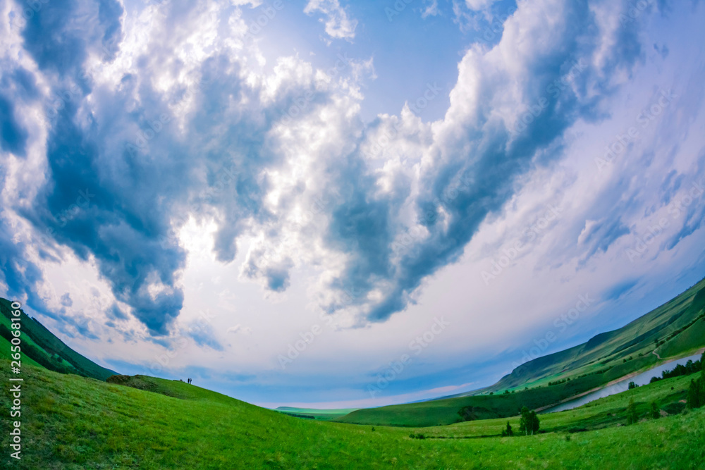The sky before the rain in a green valley through a fisheye lens