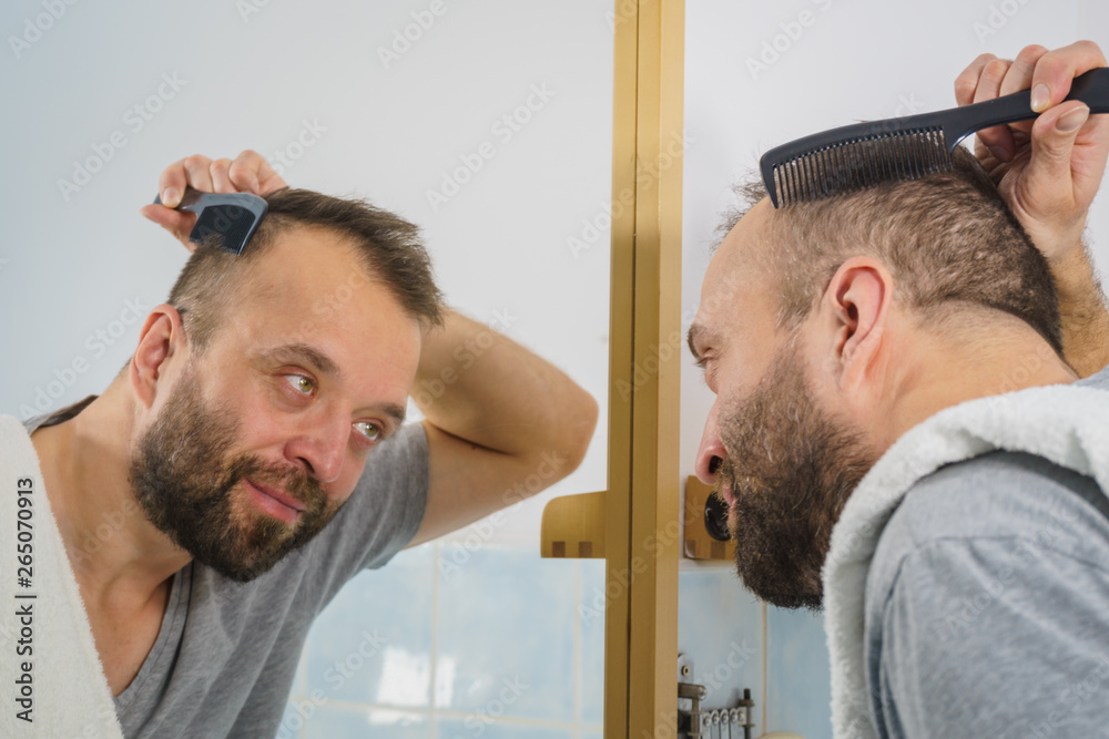 Fototapeta premium Man using comb in bathroom