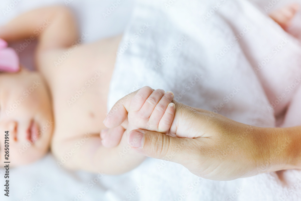 Hand of sleeping baby in the hand of mother close-up on the bed