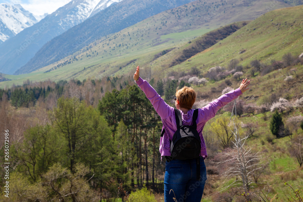 Girl with a backpack on the background of spring mountains. Beautiful mountain gorge. Nature and adventure.
