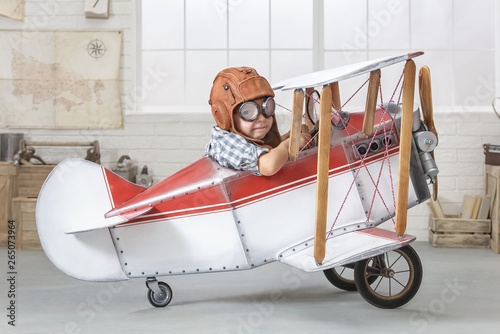 Little boy in the guise of a pilot at the helm of a toy-airplane