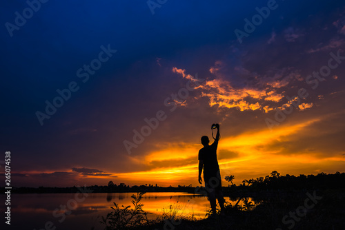 Silhouette photographer at sunset on the lake landscape