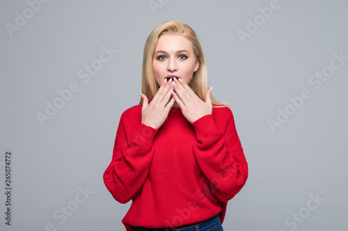 Portrait of amazed young blonde woman over gray background