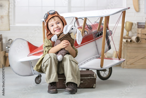 Little boy in the image of the pilot near the toy-plane