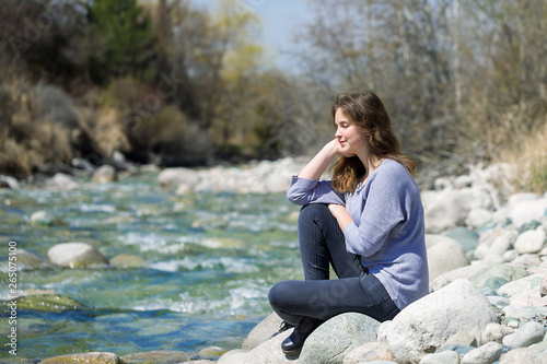 Young girl with positive emotions. Relaxed, pleased with a smile on her face. Spring natural background, forest and river.