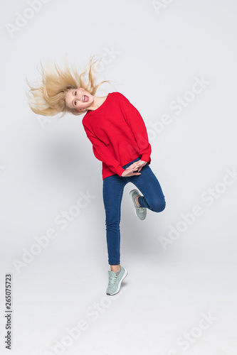 Full length portrait of woman wearing jeans and t-shirt jumping and rejoicing with perfect smile isolated over gray background