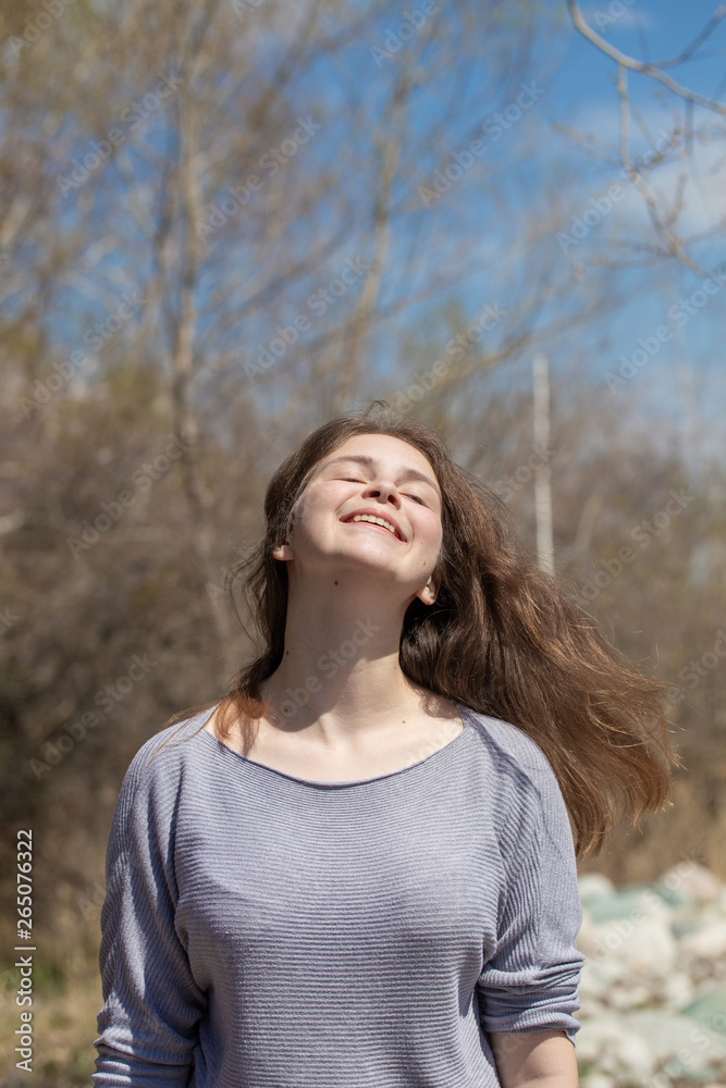 Young girl on nature with positive emotions. Relaxed, pleased with a smile on her face. Twists his head. Carefree fun pastime.