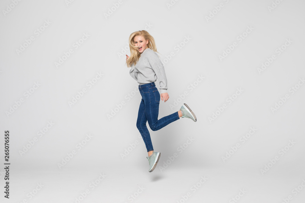 Full length portrait of a cheerful young woman jumping and celebrating over gray background Full length portrait of a cheerful young woman jumping and celebrating over gray background