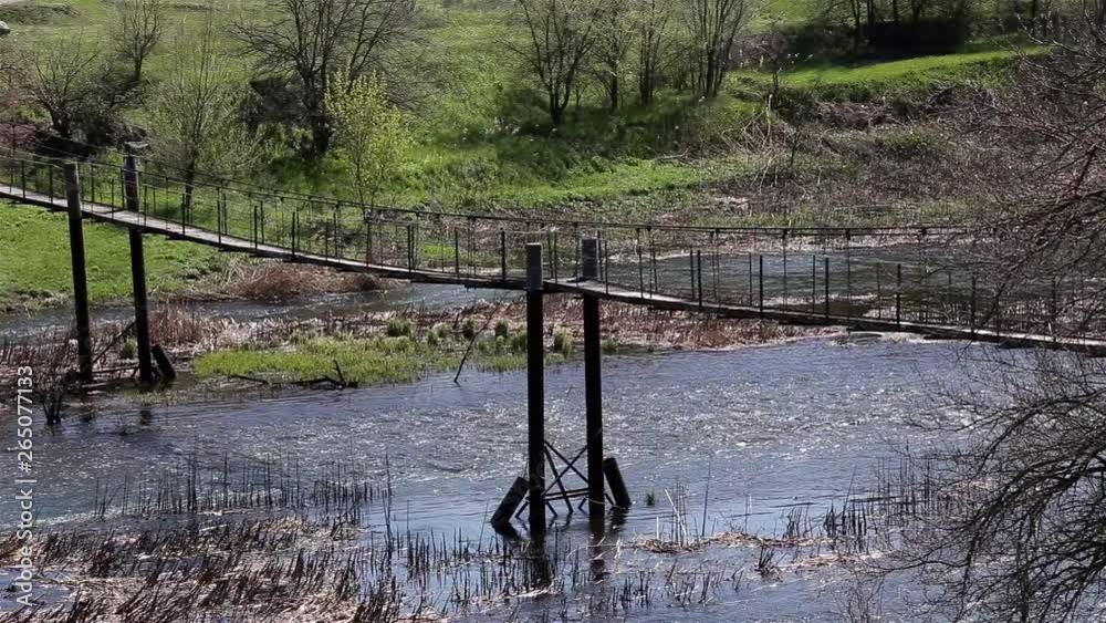 Old Empty Metal Pedestrian Bridge Across Small River At Countryside On Sunny Day Old Empty Metal Pedestrian Bridge Across Small River At Countryside On Sunny Day