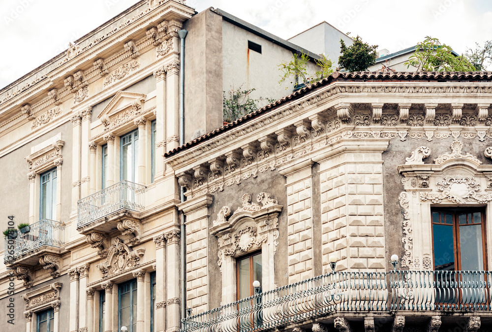 Balcony with flowerpots and house plants in a historic building in Catania, traditional architecture of Sicily, Italy.