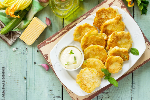 Tableau sur toile Vegan vegetable fritters zucchini and sour cream garlic sauce on the kitchen wooden table