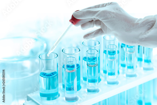 Test tubes with liquid in laboratory, Doctor hand holding dropper with dripping  or transparent glass pipette, dropper for instillation nose or eyes.