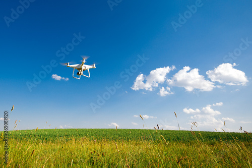 the white drone in hands at the man isolated against the background of the green field