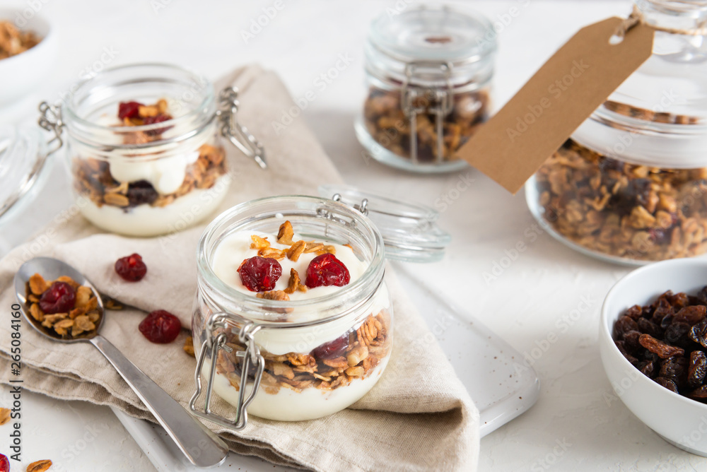 Homemade granola with nuts, fruits and yogurt in jars on white background. Healthy food, dieting. breakfast time. Copy space