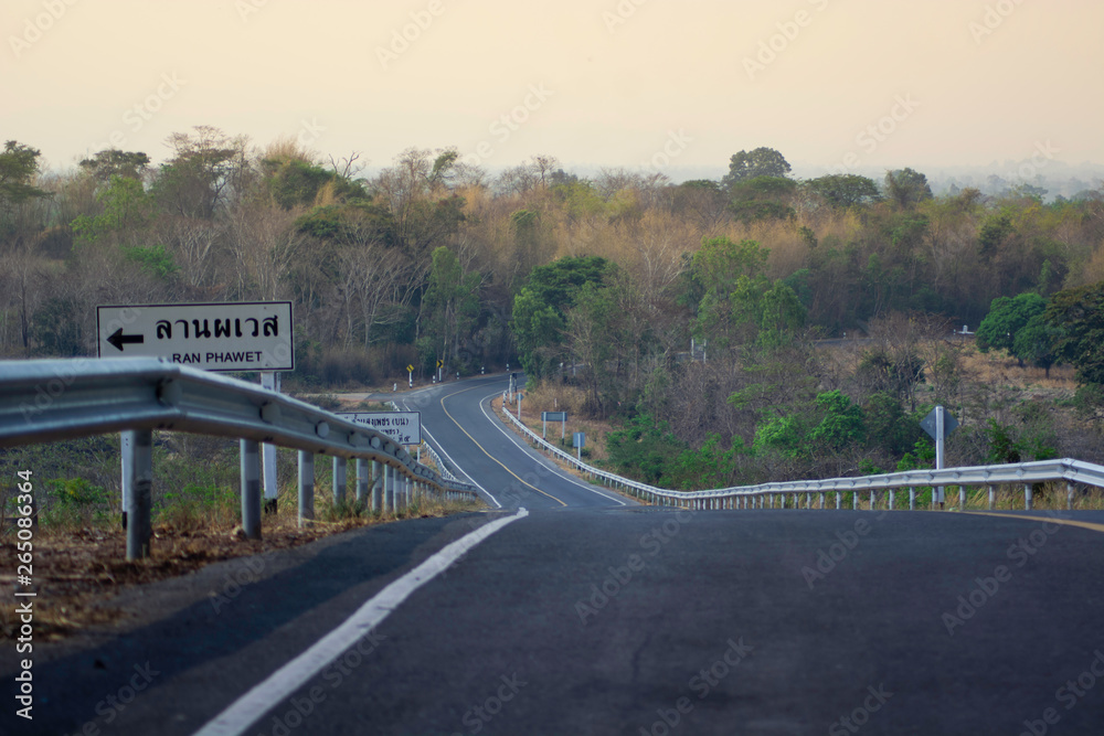 Naklejka premium The road has a yellow line and there is a warning sign on the steep left side down from him.