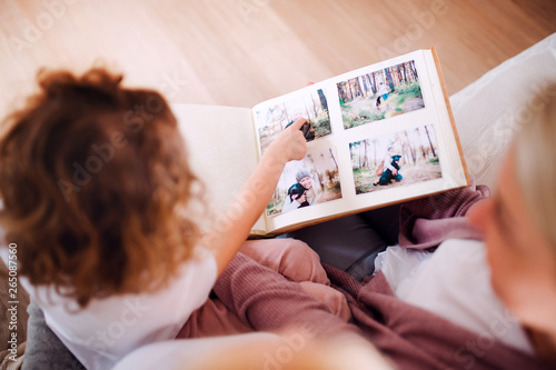 A small girl with mother and grandmother at home, looking at photographs.