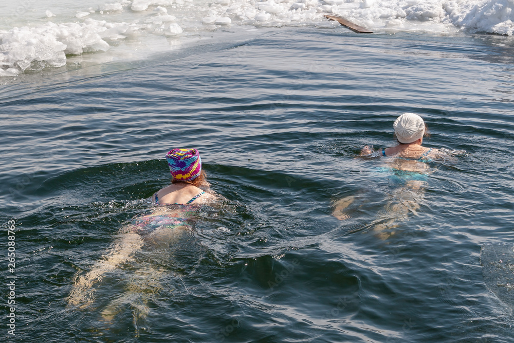 A man - a winter swimmer, swimming in the winter hole.