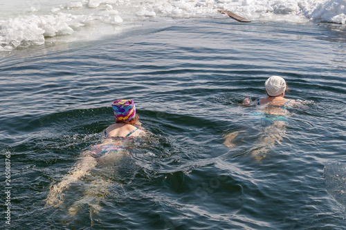 A man - a winter swimmer, swimming in the winter hole.