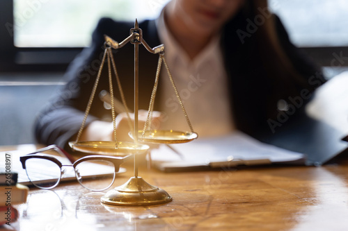 Scales of justice on wooden table background with Professional female lawyers working at the law firms . Concepts of law.