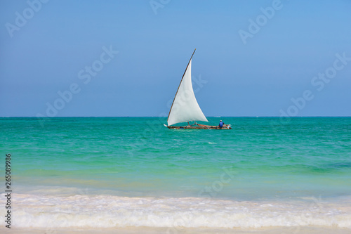 Fisherman sitting in dhow boat sailing blue waters