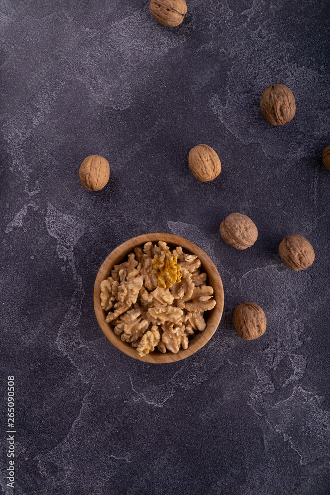 Cracked and whole walnuts in wooden bowl and on blue slate surface. Healthy nuts and seeds composition. Cracked and whole walnuts in wooden bowl and on blue slate surface. Healthy nuts and seeds composition.