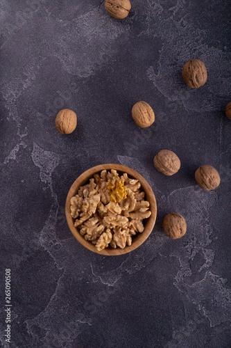 Cracked and whole walnuts in wooden bowl and on blue slate surface. Healthy nuts and seeds composition.