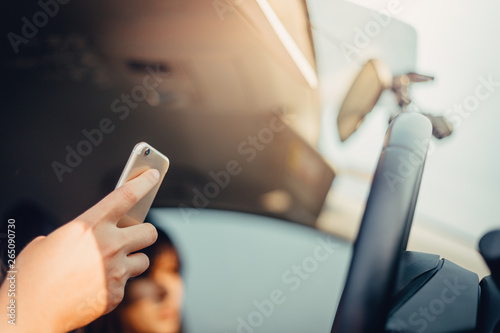 Young woman driving the car and use the phone while driving. sun shines through front window. sun shines through front window. Blurred background and Soft focus.