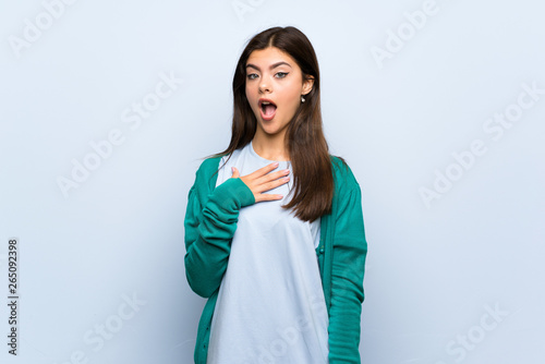 Teenager girl over blue wall surprised and shocked while looking right © luismolinero