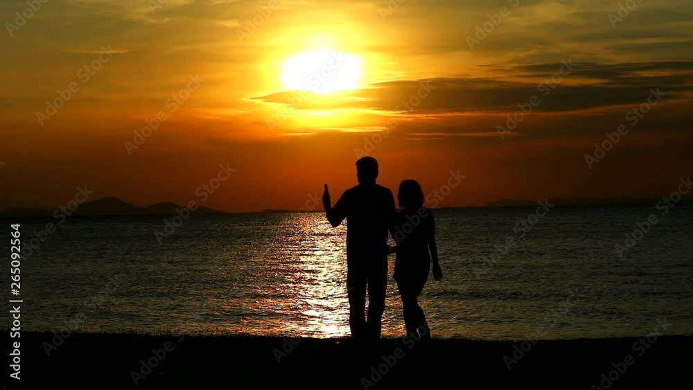 Couple lover taking selfies and hugged while sunset on the sea Couple lover taking selfies and hugged while sunset on the sea