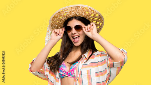 Teenager girl on summer vacation with glasses and surprised over isolated yellow background