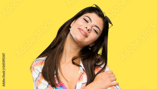 Teenager girl on summer vacation hugging over isolated yellow background
