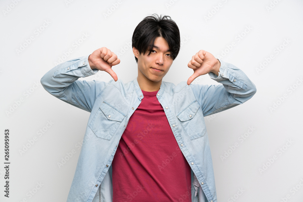Asian man on isolated white background showing thumb down Asian man on isolated white background showing thumb down
