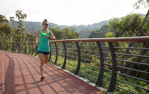 Runner athlete running on spring forest trail. woman fitness jogging workout wellness concept.