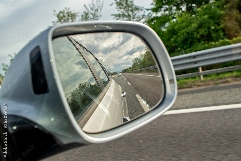 Closeup of a rear view mirror, empty road in the mirror