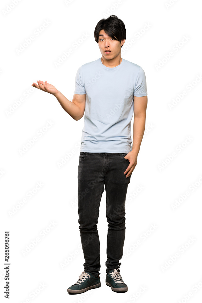 A full-length shot of a Asian man with blue shirt making doubts gesture over isolated white background A full-length shot of a Asian man with blue shirt making doubts gesture over isolated white background