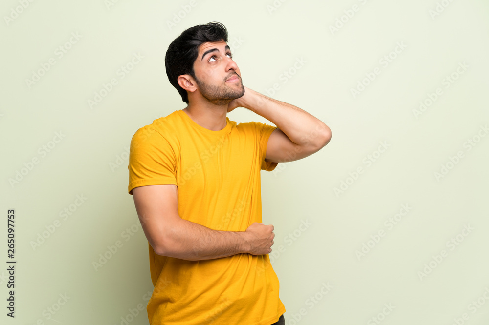 Young man over pink wall thinking an idea while scratching head