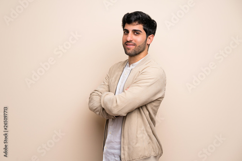 Young man over isolated wall with arms crossed and looking forward
