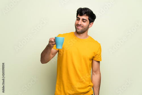 Young man over pink wall holding a hot cup of coffee