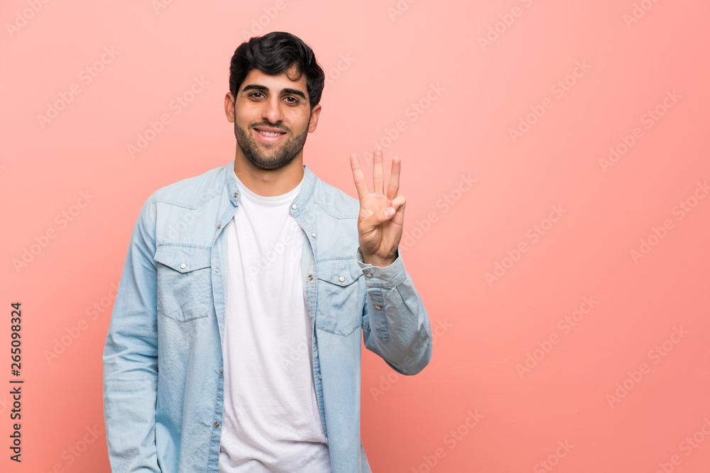Young man over pink wall happy and counting three with fingers Young man over pink wall happy and counting three with fingers