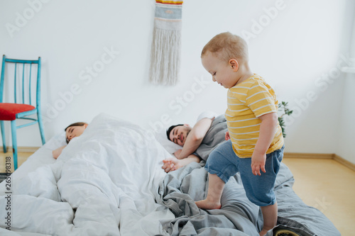 Bild auf Leinwand Cute little son trying to wake up his parents.
