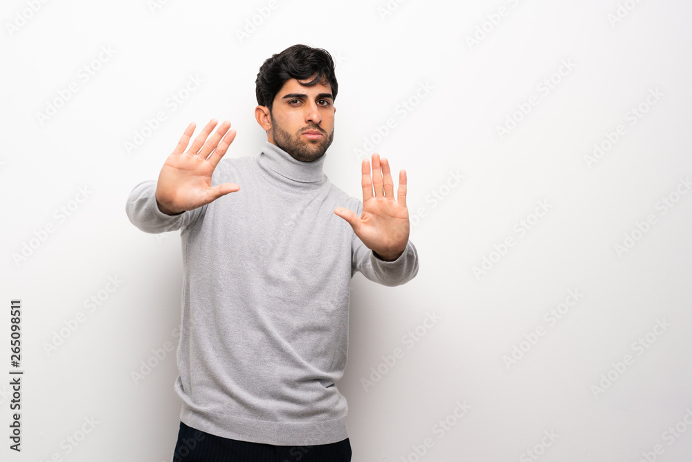 Young man over isolated white wall making stop gesture and disappointed Young man over isolated white wall making stop gesture and disappointed